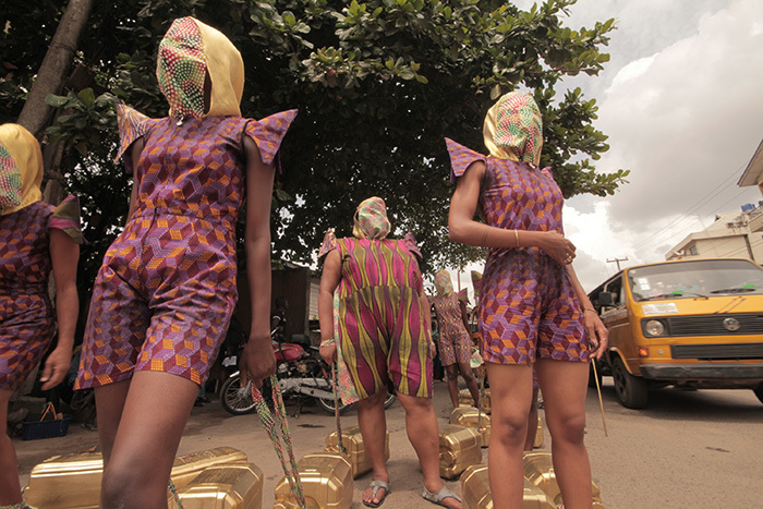KWuru-Natasha's <i>Can't I just decide to fly?</i> is a public endurance performance, in which a group of masked women haul water kegs through the streets of Cape Town, exploring the relationship between physical labour, beauty and social change.</i>