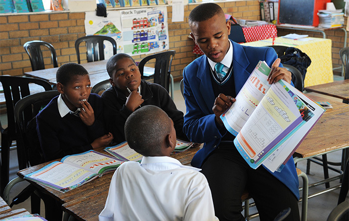 A Grade 11 student from the Centre of Science and Technology (COSAT) in Khayelitsha helps Grade 6 learners from Intshayelelo Primary during the homework club established to help the younger learners improve among others their systemic test results.