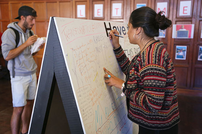 A student writes a comment on one of the 'Have Your Say' boards on campus. (Photo by Je'nine May.)