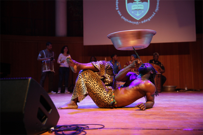 Guest Kofi Lartey performed a fire dance, which adapts contemporary fire-dancing techniques to popular kpanlogo rhythms of Ghana. Lartey is a Ghanaian master drummer and dancer who has contributed much to the College of Music's programme in recent months. Here he controls a spinning bowl while executing an acrobatic dance.