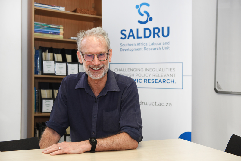 Director of the Southern Africa Labour and Development Research Unit (SALDRU), Prof Murray Leibbrandt, with the new SALDRU logo in the background. <b>Photo</b> Robyn Walker.