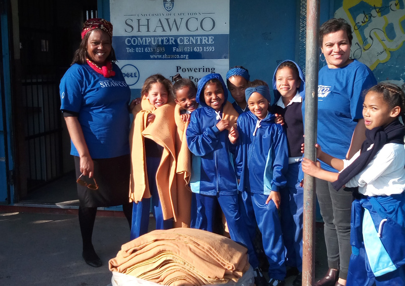 SHAWCO office administrator Thembisa Nkwaba and house keeper of SHAWCO House Belinda Martin with some of the learners who have benefitted from SHAWCO’s winter-warmth drive on Mandela Day.