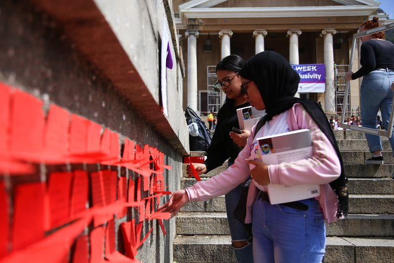 Students interact with the installation which allowed viewers to share their personal interpretations of how GBV impacts the UCT community, writing comments on rectangles of red paper placed along the steps leading up to the Plaza.