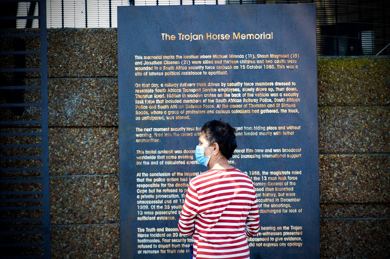 A passer-by engages with the storyboard at the Trojan Horse Massacre memorial, which is located in Thornton Road in Athlone, Cape Town.
