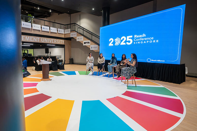 Natasha Haffajee (speaking into microphone) joins a panel at the Reach Alliance 2025 Conference. 