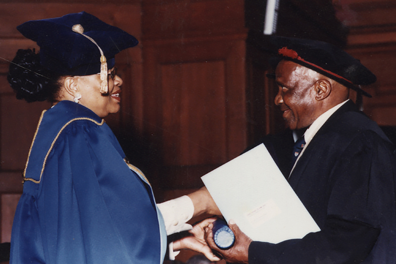 Hamilton Naki receives his honorary MSc in medicine from  UCT Chancellor Graça Machel in 2003. Naki was an informally taught surgical technician at Groote Schuur Hospital where he  started working as a gardener and cleaner before becoming the hospital’s principal lab technician. He eventually helped to teach over 3 000 surgeons, and assisted with Chris Barnard's organ transplant programme.