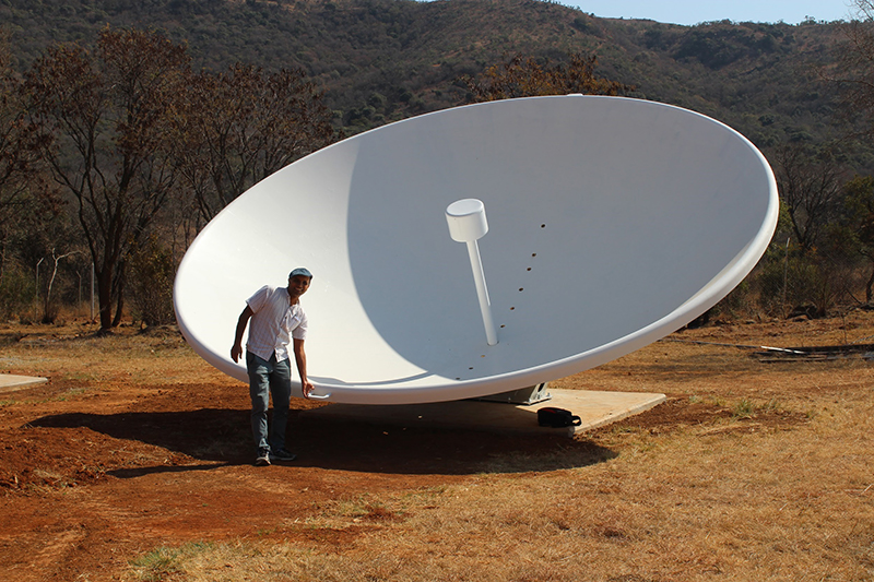 Kavilan Moodley, professor at the University of KwaZulu-Natal and principal investigator of HIRAX, alongside one of the newly installed prototype dishes.
