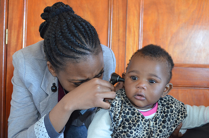 SHAWCO Health volunteer supervisor and fourth-year audiology student Sola Mcgogo conducts a health check on one of the young patients visiting the paediatric clinic at Tambo Village on Saturday, 22 August 2015.