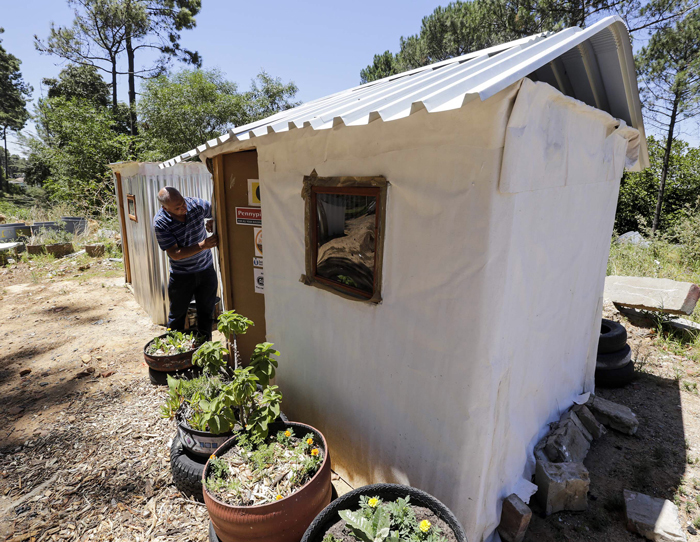 Mark Algra shows off the shack blanket he designed. The shack on the left is a standard shack and the one on the right is an experimental shack at the University of Cape Town. Photo by Adrian de Kock.