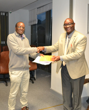 Dr Manya Mooya presents a copy of his book to Mr Christopher Gavor, the valuer-general.
