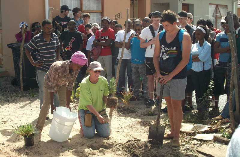 Community roots: Alison Coutras of Green Communities helps a new Witsand homeowner plant their demo garden, in the company of UCT first-year construction and property studies students and community members.