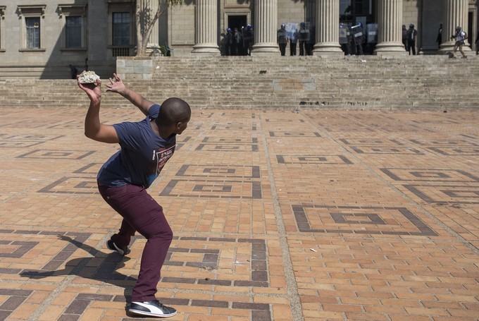A student protester throws a rock towards security guards during a protest at Wits University. 