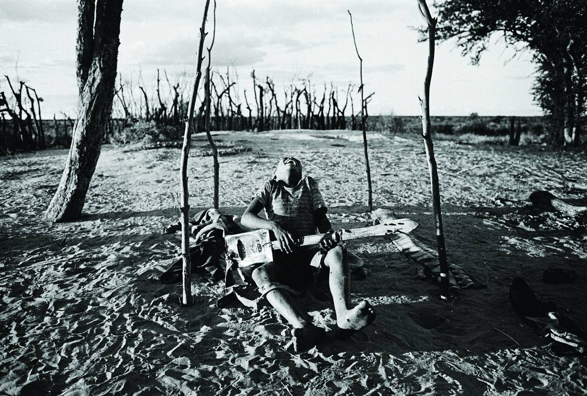 Boy playing a homemade guitar. Bushmanland, Namibia, 1987.