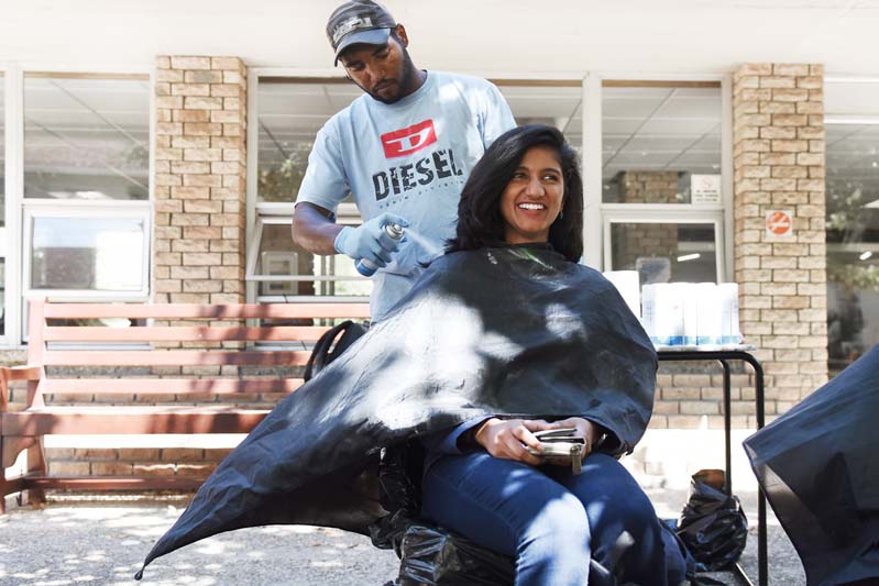 A student prepares to have her hair sprayed in support of cancer awareness.