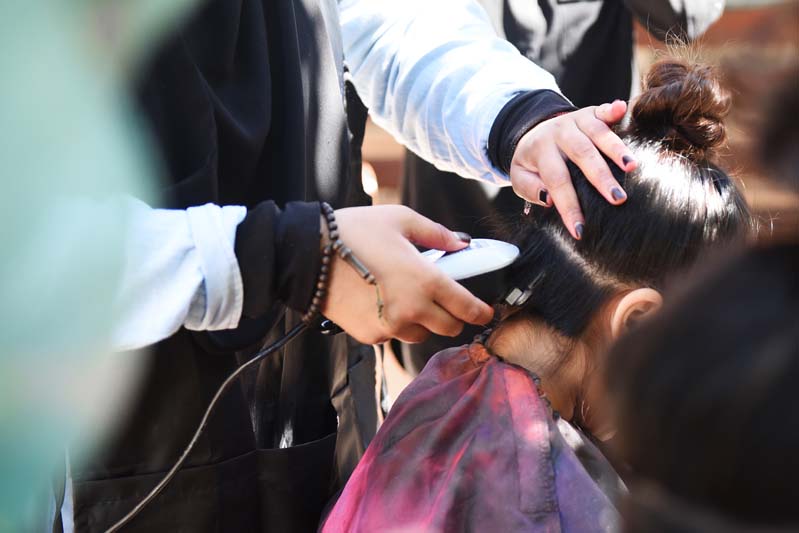 A student gets the underside of her hair cut and shaved.