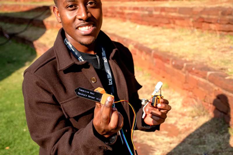 Maile demonstrates his team’s capacitive soil moisture sensor, designed to measure when crops actually need water and help prevent over or under watering.